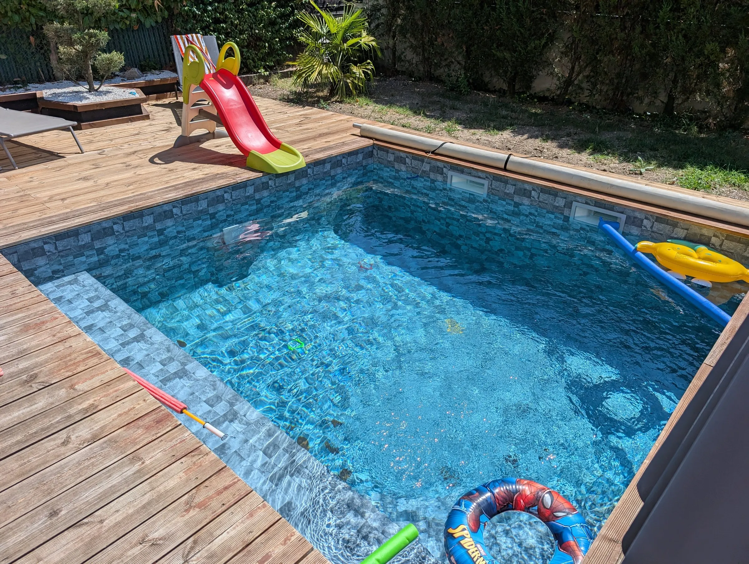 Piscine en mosaïque bleue entourée d’une terrasse en bois